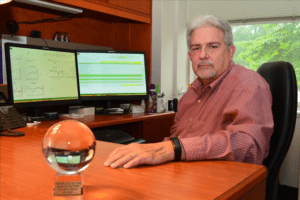 A man sitting at his desk with a glass ball in front of him.
