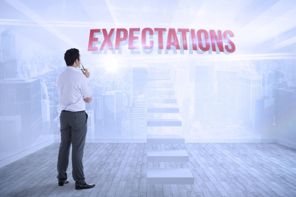 A man standing in front of the word expectations.