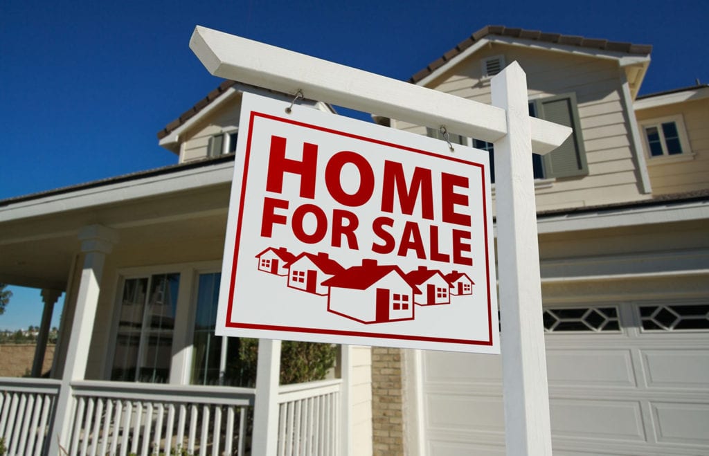 A home for sale sign in front of a house.