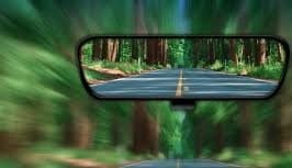 A rear view mirror of a car with trees in the background