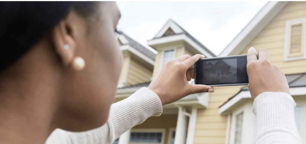 A person taking a picture of a house with their phone.