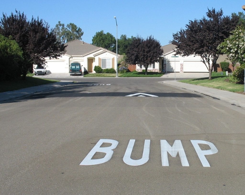 A street sign that says bump in the middle of the road.