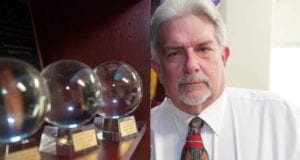 A man standing next to two glass balls.