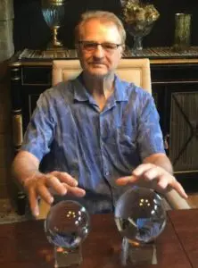 A man sitting at a table with two crystal balls.